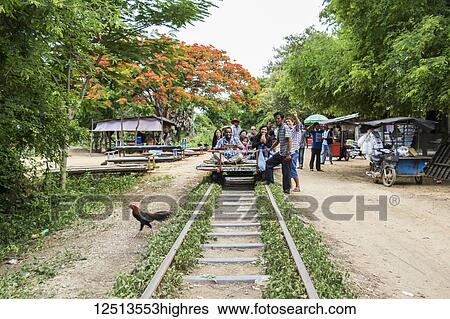 Stock Photograph - People sitting on a Norry, the bamboo train, at the Norry Railway Station; Battambang, Cambodia. Fotosearch