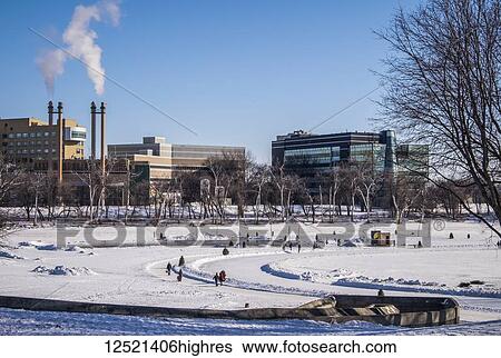 Stock Photograph - People walking and skating along the Red River Mutual Trail in Winnipeg, where artistic warming huts are on display; Winnipeg, Manitoba, Canada. Fotosearch