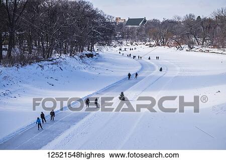 Stock Photograph - People walking and skating along the Red River Mutual Trail; Winnipeg, Manitoba, Canada. Fotosearch