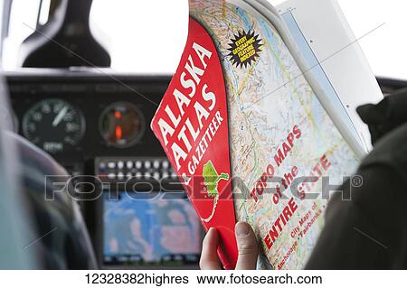 Stock Photograph - Person Holding An Alaska Atlas & Gazetteer In The Cockpit Of An Airplane, Alaska, USA. Fotosearch