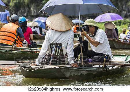 Photographer in a boat on the Ngo Dong River; Tam Coc, Ninh Binh, Vietnam View Large Photo Image Stock Photograph - Photographer in a boat on the Ngo Dong River; Tam Coc, Ninh Binh, Vietnam. Fotosearch