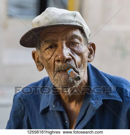 Stock Photograph - Portrait of a senior Cuban man smoking a cigar; Havana, Cuba. Fotosearch