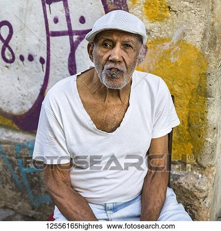 Stock Photograph - Portrait of a senior Cuban man smoking a cigar; Havana, Cuba. Fotosearch