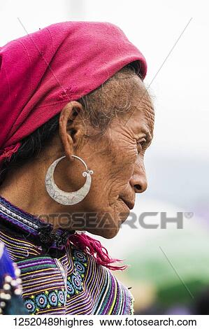 Stock Photograph - Portrait of a senior woman wearing a headscarf and earrings with colourful dress; Bac Ha, Lao Cai, Vietnam. Fotosearch