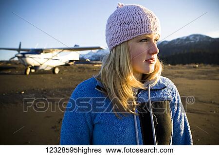 Stock Photograph - Portrait of a woman on a beach with a bush plane in the background, Kachemak Bay State Park, South-central Alaska; Alaska, United States of America. Fotosearch