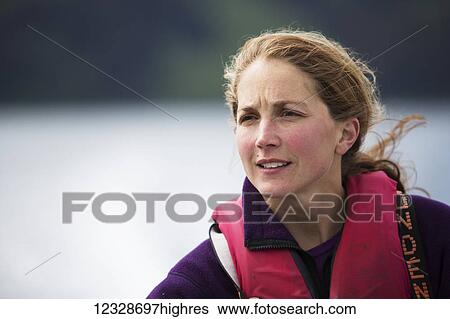 Stock Photograph - Portrait of a woman wearing a life vest and hair blowing in the wind, South-central Alaska; Alaska, United States of America. Fotosearch