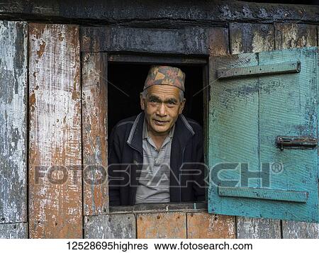 Stock Photograph - Portrait of an Indian man looking out a window; Radhu Khandu Village, Sikkim, India. Fotosearch