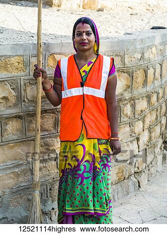 Portrait of an Indian woman wearing a reflective vest and holding a broom; Jaisalmer, Rajasthan, India View Large Photo Image Stock Photograph - Portrait of an Indian woman wearing a reflective vest and holding a broom; Jaisalmer, Rajasthan, India. Fotosearch