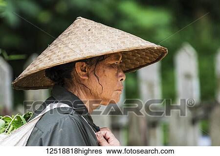 Stock Photograph - Portrait of the profile of a senior woman wearing a woven conical hat, Elephant Village; Luang Prabang, Laos. Fotosearch