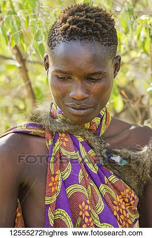 Stock Photograph - Portrait of young Hadzabe hunter wearing baboon skin cloak and colorful clothing near Lake Eyasi; Tanzania. Fotosearch