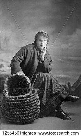 Stock Photograph - Postcard circa 1900, Victorian/Edwardian Social History. A portrait of a fisherlass from Cullercoats with her basket; Cullercoats, England. Fotosearch