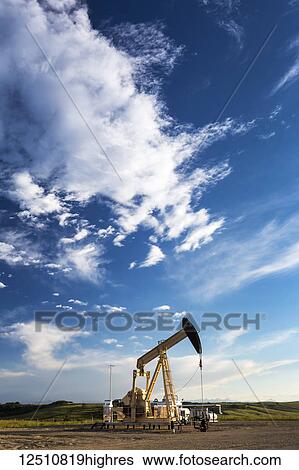 Pumpjack with dramatic clouds and blue sky at sunset, West of Airdrie; Alberta, Canada View Large Photo Image Stock Photograph - Pumpjack with dramatic clouds and blue sky at sunset, West of Airdrie; Alberta, Canada. Fotosearch