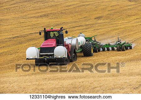 Stock Photograph - Quadtrac Tractor Pulling An Anhydrous Ammonia Tank And Applicator Applying The Anhydrous To A Field In Advance Of Preparing It For Planting In The Palouse Region Of Eastern Washington; Washington, United States Of America. Fotosearch