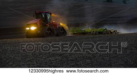 Stock Photograph - Quadtrac Tractor Seeding Garbanzo Beans At Dusk In The Palouse Region Of Eastern Washington; Washington, United States Of America. Fotosearch