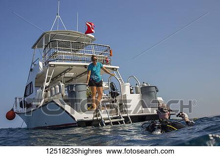 Stock Photograph - Scuba diver being greeted by dive boat captain at end of dive off the Kona coast; Island of Hawaii, Hawaii, United States of America. Fotosearch