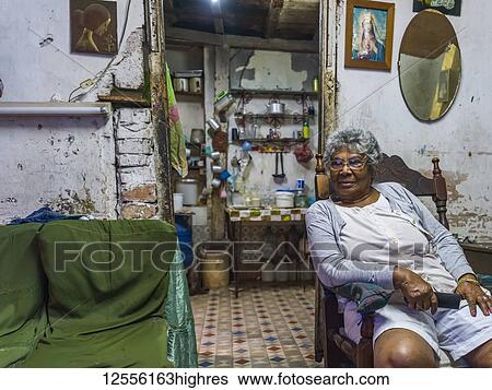 Senior Cuban woman sits in a chair in her home; Havana, Cuba View Large Photo Image Stock Photograph - Senior Cuban woman sits in a chair in her home; Havana, Cuba. Fotosearch