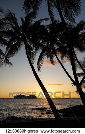 Stock Photograph - Silhouette of a cruise ship on the water off the shore of Kailua Bay at sunset; Kailua-Kona, Island of Hawaii, Hawaii, United States of America. Fotosearch