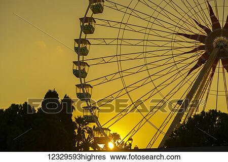 Stock Photograph - Silhouette Of A Ferris Wheel Against A Golden Sky At Sunset, Place Massena; Nice, Cote D'azur, France. Fotosearch