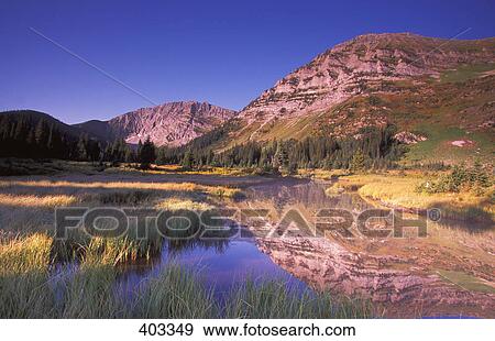 Stock Photo - Small reed-filled lake surrounded by mountains. Fotosearch