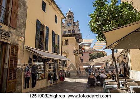 Small shops and restaurants along a narrow street; Alcudia, Mallorca, Balearic Islands, Spain View Large Photo Image Stock Photograph - Small shops and restaurants along a narrow street; Alcudia, Mallorca, Balearic Islands, Spain. Fotosearch