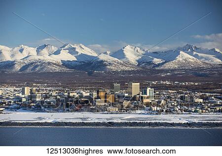 Stock Photograph - Snow-covered downtown Anchorage with the Chugach Mountains directly in the background, South-central Alaska; Anchorage, Alaska, United States of America. Fotosearch