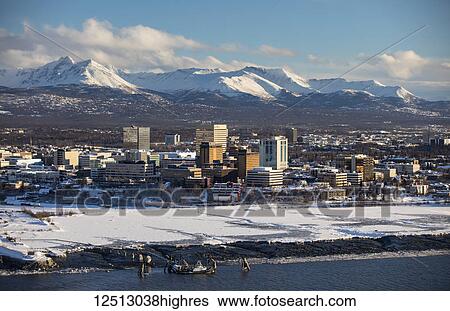 Stock Photograph - Snow-covered downtown Anchorage with the Chugach Mountains directly in the background and Cook Inlet in the foreground, South-central Alaska; Anchorage, Alaska, United States of America. Fotosearch