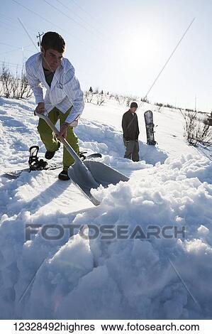 Snowboarder clearing snow with a shovel, South-central Alaska, Homer, Alaska, United States of America View Large Photo Image Stock Photograph - Snowboarder clearing snow with a shovel, South-central Alaska, Homer, Alaska, United States of America. Fotosearch