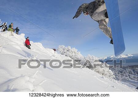 Stock Photograph - Snowboarder making a jump on a hillside, Homer, Southcentral Alaska, USA. Fotosearch