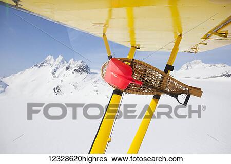 Stock Photograph - Snowshoes and small shovel attached to the wing of a Piper Super Cub while in flight, Kenai Mountains, Kachemak Bay State Park, South-central Alaska; Alaska, United States of America. Fotosearch