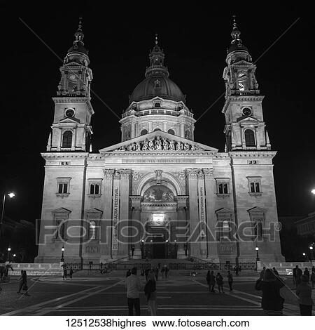 Stock Photograph - St. Stephen's Basilica at nighttime with tourists on the street; Budapest, Budapest, Hungary. Fotosearch