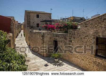 Stone walls and houses on a street under a blue sky in the Mediterranean; Alcudia, Mallorca, Balearic Islands, Spain View Large Photo Image Stock Photograph - Stone walls and houses on a street under a blue sky in the Mediterranean; Alcudia, Mallorca, Balearic Islands, Spain. Fotosearch