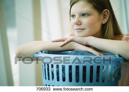Stock Image - Student rests on laundry basket. Fotosearch