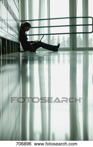 Stock Photograph - Student sitting by lockers. Fotosearch