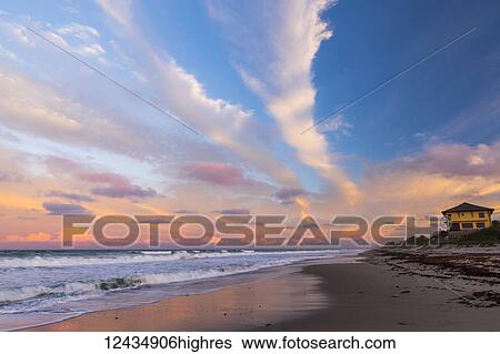 Stock Photograph - Sunset over a beach and yellow house on the Atlantic coast; Satellite Beach, Florida, United States of America. Fotosearch