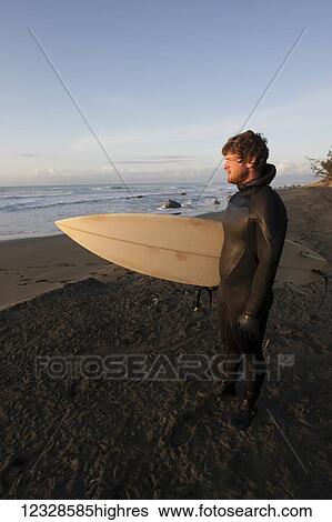 Surfer holding surfboard looking at ocean at sunset, Southeast Alaska; Yakutat, Alaska, United States of America View Large Photo Image Stock Photograph - Surfer holding surfboard looking at ocean at sunset, Southeast Alaska; Yakutat, Alaska, United States of America. Fotosearch