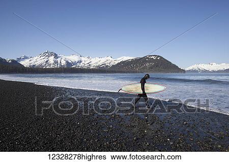 Stock Photograph - Surfer On The Beach With His Surfboard, Kenai Peninsula Outer Coast, Southcentral Alaska, USA. Fotosearch