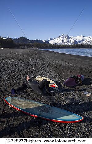 Surfer Resting On The Beach Alongside Surfboards, Kenai Peninsula Outer Coast, Southcentral Alaska, USA View Large Photo Image Stock Photograph - Surfer Resting On The Beach Alongside Surfboards, Kenai Peninsula Outer Coast, Southcentral Alaska, USA. Fotosearch