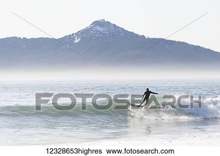 Surfer riding a wave along the Kenai Peninsula Outer Coast, South-central Alaska, USA View Large Photo Image Stock Photograph - Surfer riding a wave along the Kenai Peninsula Outer Coast, South-central Alaska, USA. Fotosearch