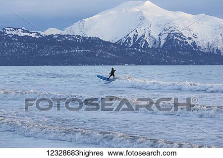 Stock Photograph - Surfer riding waves in Kachemak Bay, South-central Alaska; Homer, Alaska, United States of America. Fotosearch