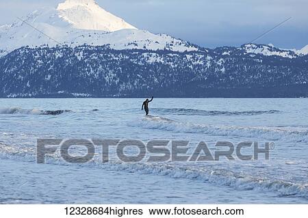 Stock Photograph - Surfer riding waves in Kachemak Bay, South-central Alaska; Homer, Alaska, United States of America. Fotosearch