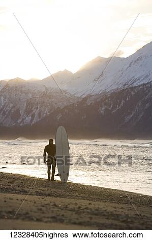 Stock Photograph - Surfer Standing With His Surfboard At Kachemak Bay, Homer Spit, Southcentral Alaska, USA. Fotosearch
