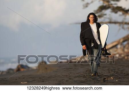 Stock Photograph - Surfer Walking With A Surfboard Along The Coast Near Yakutat, Southeast Alaska, USA. Fotosearch
