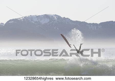 Stock Photograph - Surfer wipes out on a wave along the Kenai Peninsula Outer Coast, South-central Alaska, USA. Fotosearch