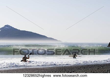 Stock Photograph - Surfers and kayaking surfer along the Kenai Peninsula Outer Coast, South-central Alaska; Alaska, United States of America. Fotosearch