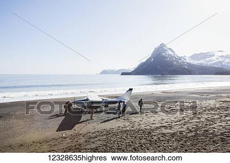 Stock Photograph - Surfers on the beach with a bush plane on a surfing trip, Outer Coast, South-central Alaska; Alaska, United States of America. Fotosearch