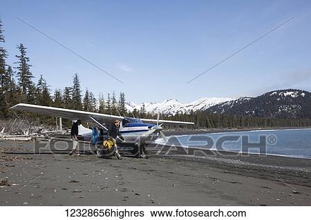 Stock Photograph - Surfers unloading gear from a Cessna 206 on the Kenai Peninsula Outer Coast, South-central Alaska; Alaska, United States of America. Fotosearch