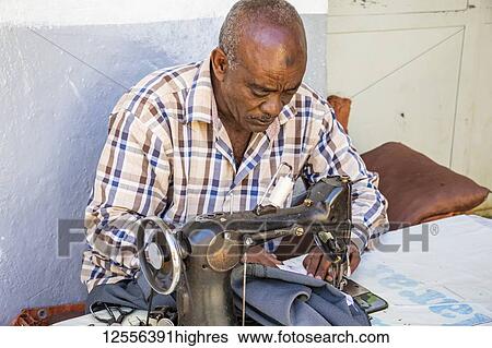 Stock Photograph - Tailor working on a vintage sewing machine in Harar Jugol, the Fortified Historic Town; Harar, Harari Region, Ethiopia. Fotosearch