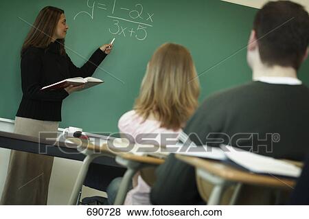Stock Photo - Teacher writes on chalk board. Fotosearch