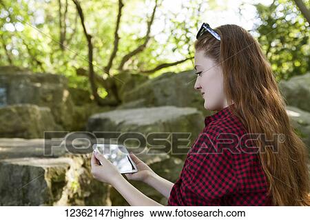 Stock Photograph - Teenage girl using her smart phone, Woodbine Beach; Toronto, Ontario, Canada. Fotosearch