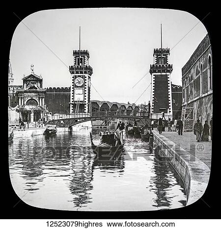 Stock Photograph - The Arsenal, Venice circa 1900 on a magic lantern slide, photograph created in 1888 by Joseph John William. Boats in the canal and pedestrians along the waterfront; Venice, Italy. Fotosearch